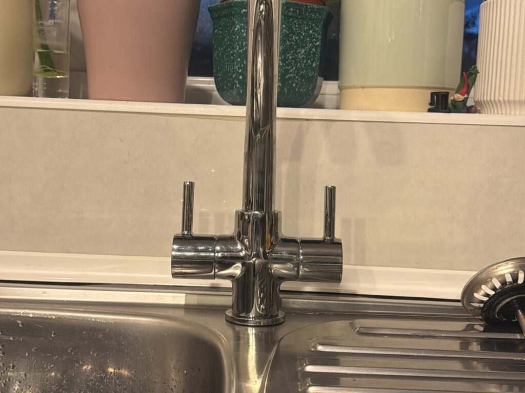 Chrome monobloc mixer tap newly fitted to a stainless steel kitchen sink.